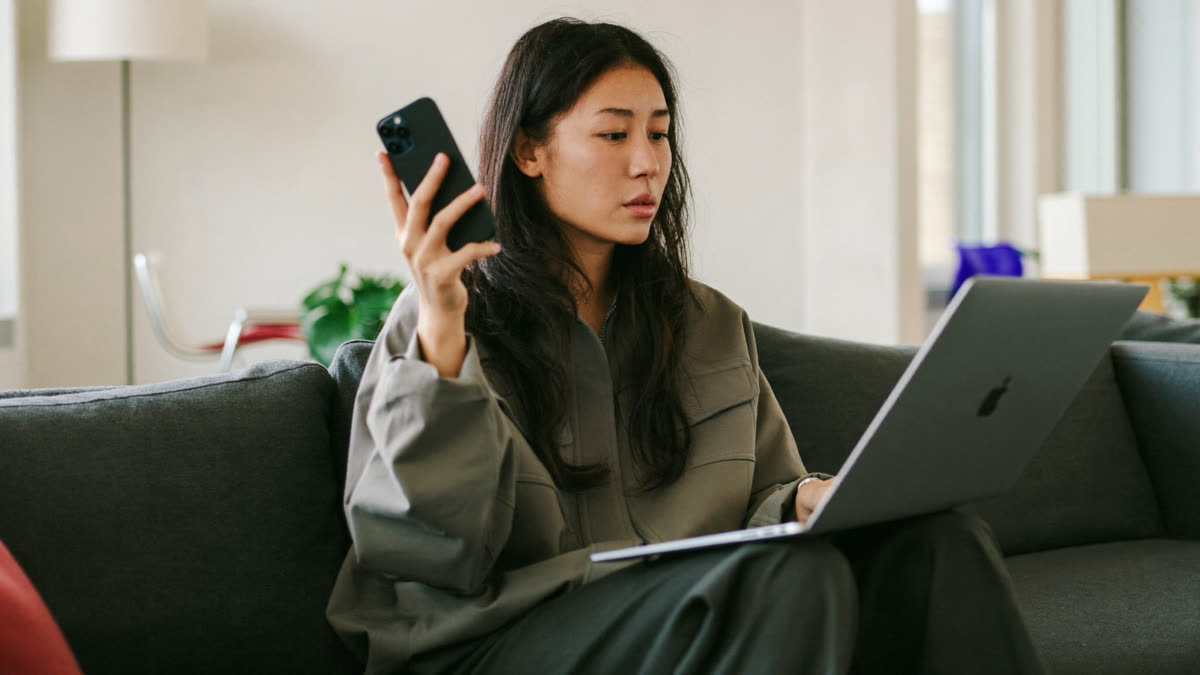 A brand manager compares an AI assistant answer on her phone with her laptop