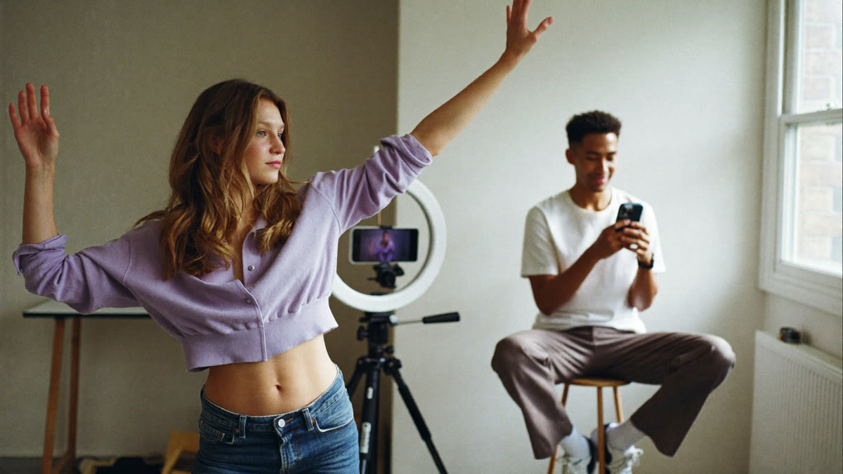 A creator films a dance move on a phone tripod while a friend watches on his phone