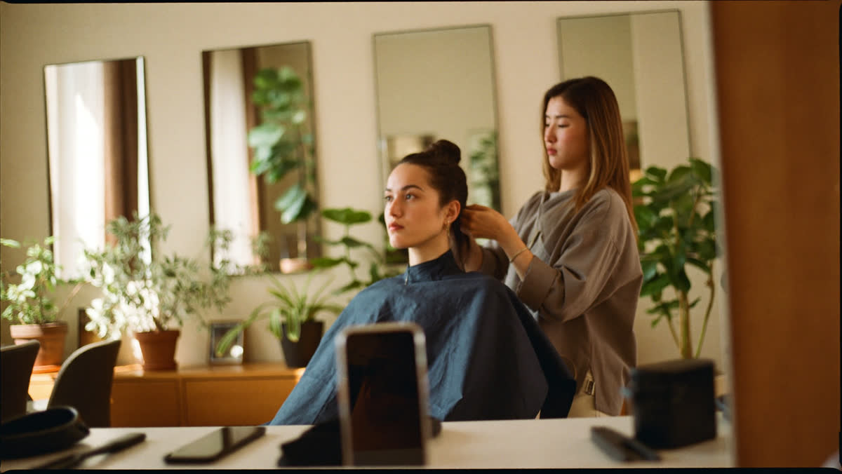 Salon owner styling a client in a bright salon
